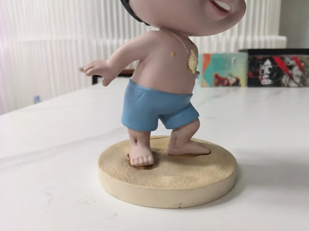 Side view close-up of a leaning PVC vinyl toy, showing the visible bending and deformation at the ankle joint caused by thermoplastic creep.