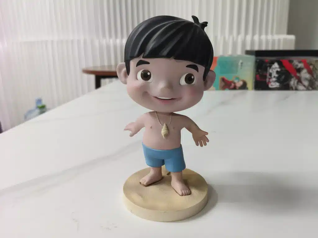 A front view of a custom chibi PVC art toy with an oversized head, demonstrating the top-heavy design that leads to 'soft leg syndrome' without proper internal support.